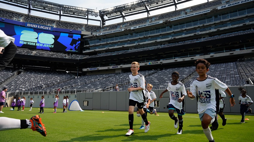 three boys run across the soccer field at metlife stadium. they are each wearing white U.S. Soccer Foundation jerseys.